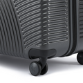 Charcoal hard-shell suitcase with textured shell and spinner wheel close-up.