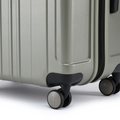 Silver suitcase corner with recessed foot, front wheels, and textured shell