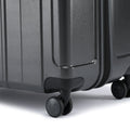Large check-in suitcase corner with recessed handle and spinner wheels on dark grey shell