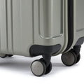 Small cabin suitcase close-up with silver-green shell, zipper edge, and 4 caster wheels.