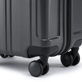 Charcoal grey hard-shell suitcase corner with rounded base, side grip and spinner wheels.