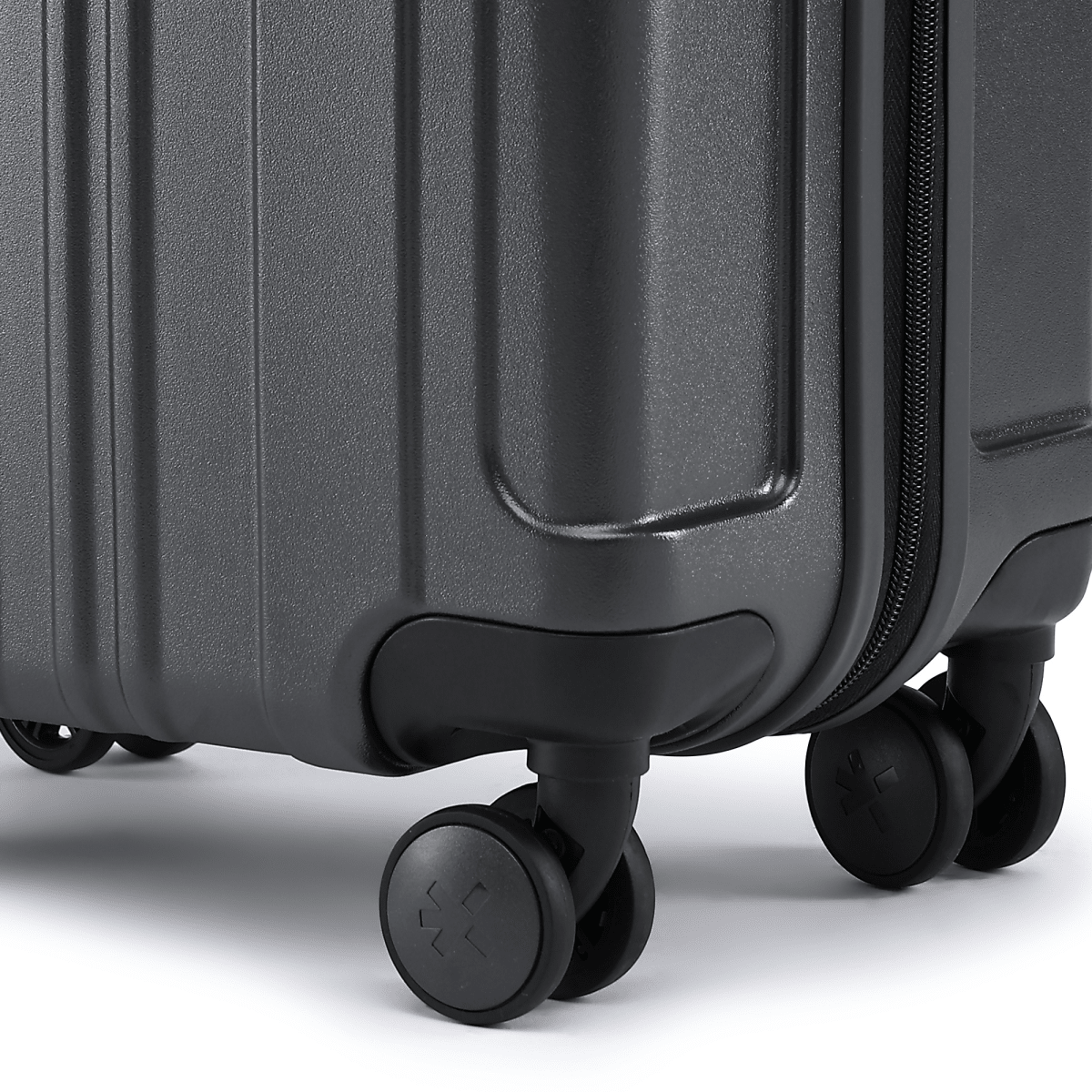 Charcoal grey hard-shell suitcase corner with bumper and 8 rolling wheels