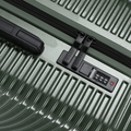 Dark green hard-shell check-in suitcase, black zipper track and lock panel detail