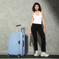 Light blue rolling suitcase with telescopic handle and four spinner wheels beside a model.