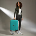Teal cabin suitcase with telescopic handle, pulled by a standing person