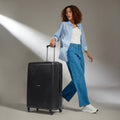 Black large suitcase with ridged shell, telescopic handle, and four wheels
