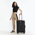 Black soft-sided spinner trolley with telescopic handle and orange-accent wheels