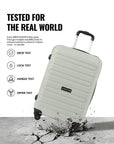 Light gray trolley suitcase with telescopic handle and 4 wheels, shown in a drop test