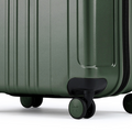 Dark green hard-shell rolling suitcase with four corner wheels and ridged panel