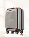 Small cabin suitcase with 8 wheels, two-tone silver and dark panels, zip top