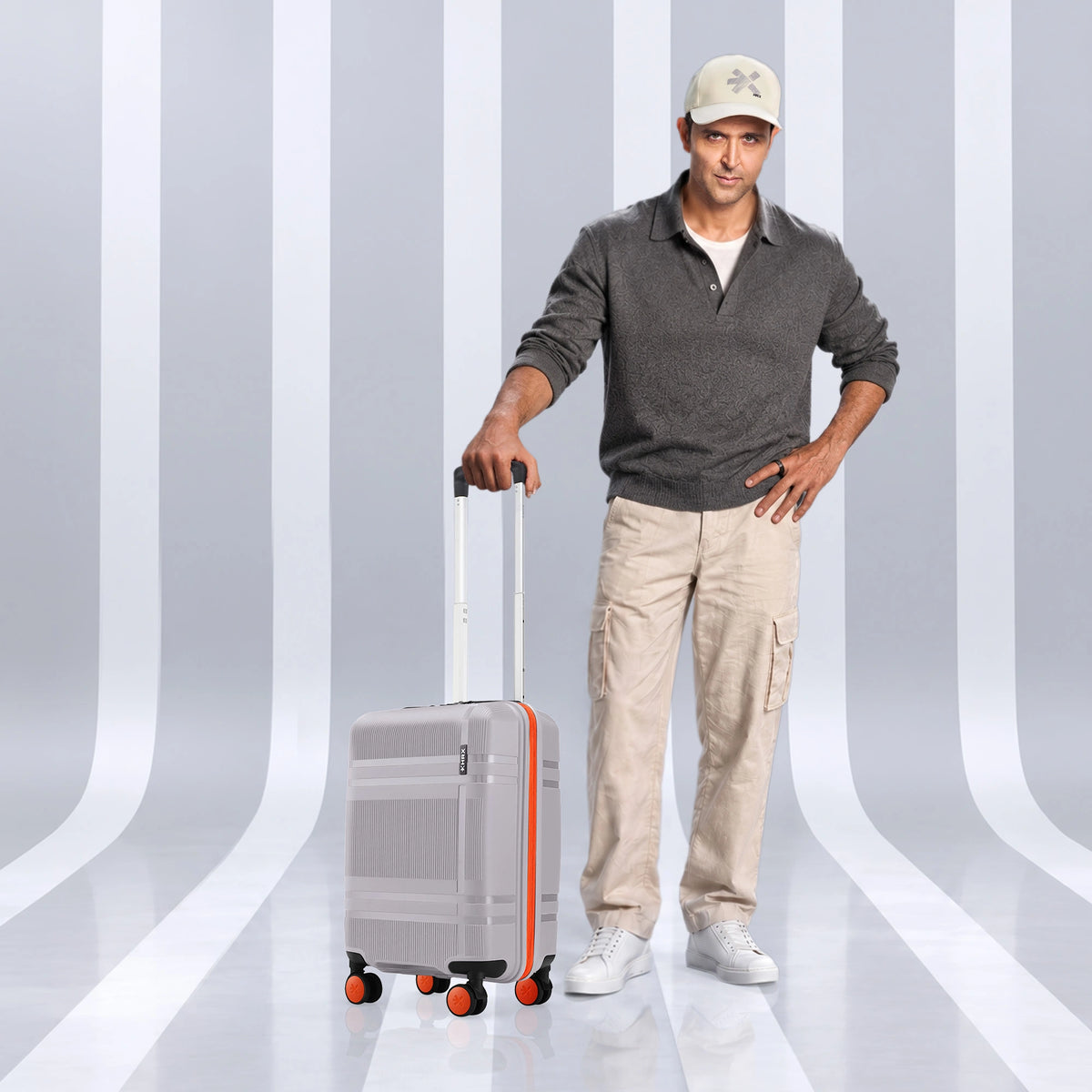 Small polycarbonate cabin suitcase, light grey with orange accents and 8 spinner wheels.
