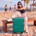 Teal medium check-in suitcase with 8 wheels standing upright on a beach