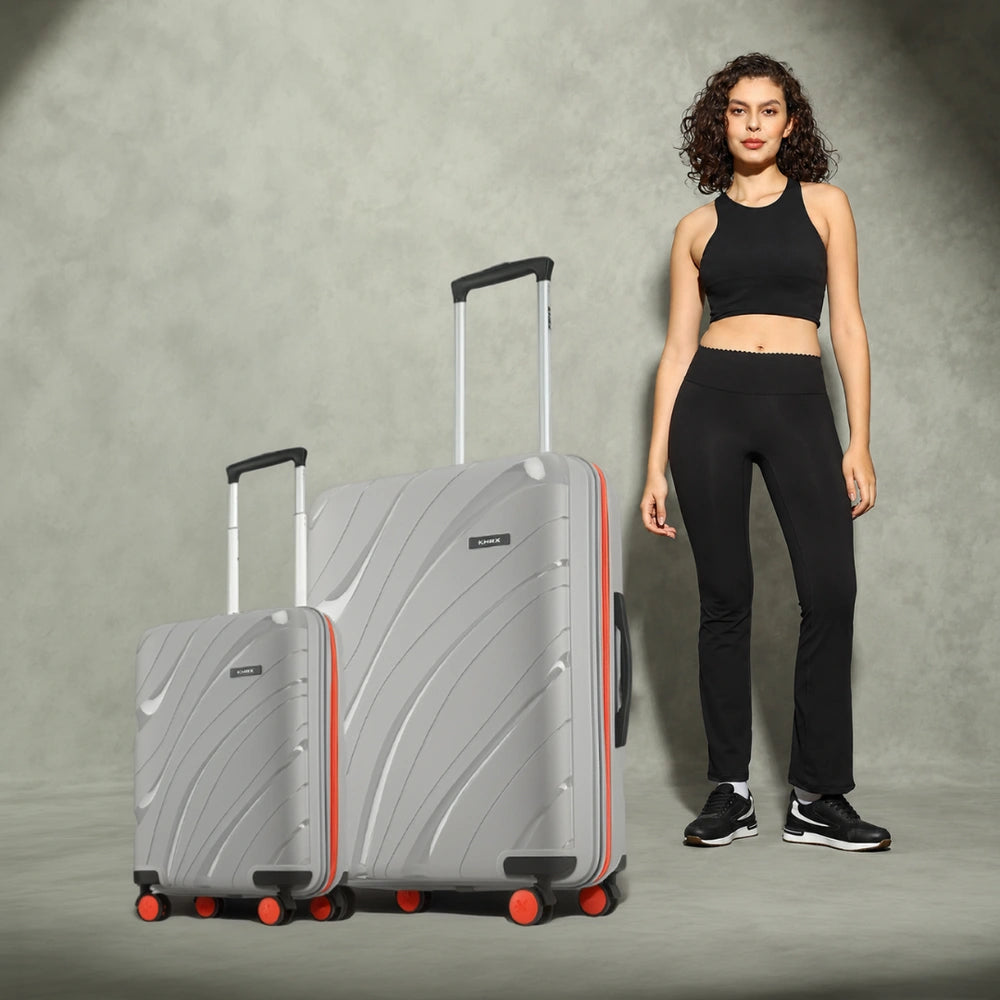 Two grey hard-shell rolling suitcases with telescopic handles and red-accent wheels