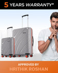 Two grey hard-shell rolling suitcases with upright telescopic handles and red-accent wheels