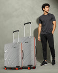 Pair of grey hard-shell rolling suitcases with telescopic handles and red wheel caps