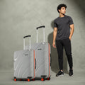 Pair of grey hard-shell rolling suitcases with telescopic handles and red wheel caps