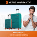 Teal hardshell cabin and large trolley suitcases with telescopic handles and spinner wheels.