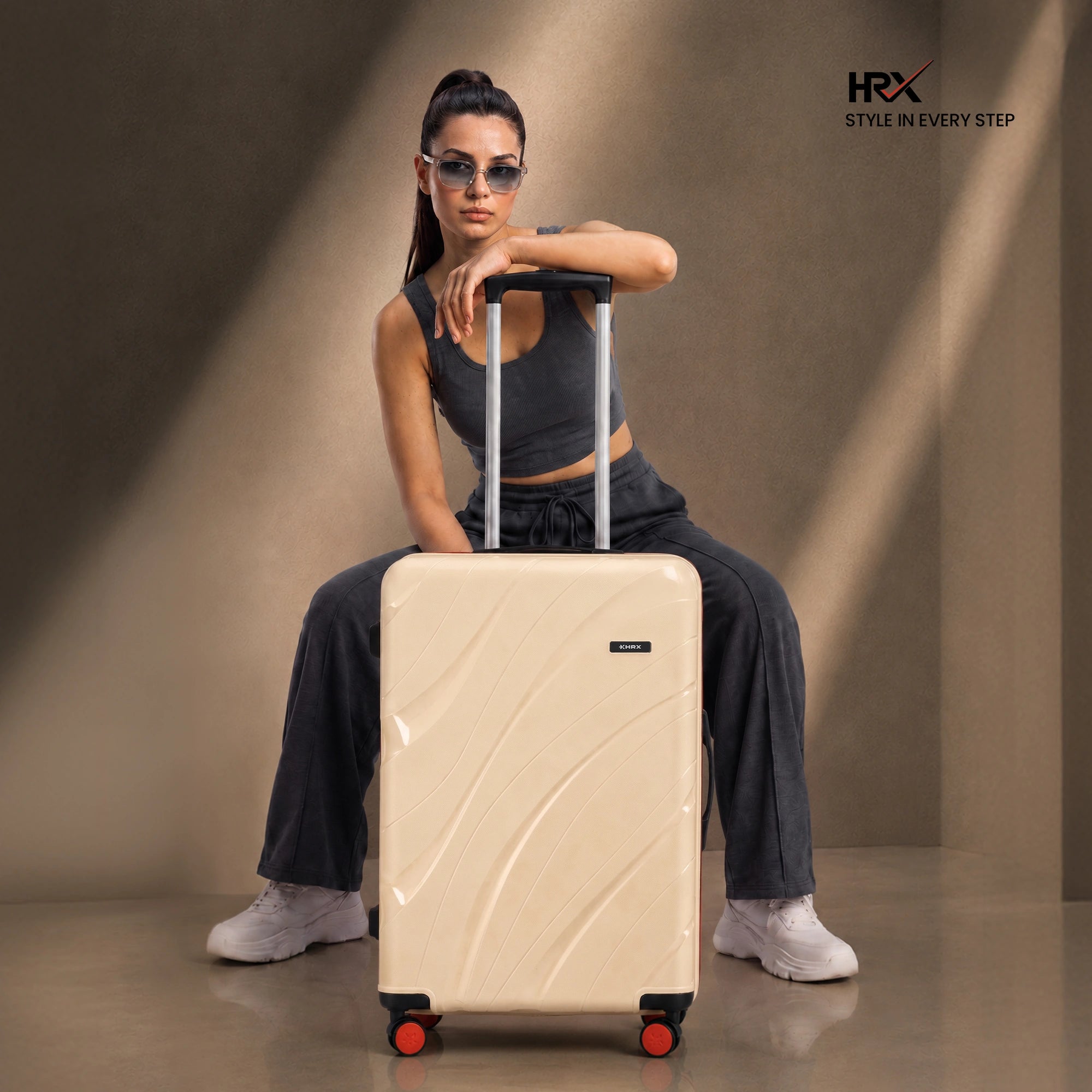 Beige cabin suitcase with trolley handle, front side panels, and four red-accent wheels