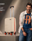 Beige small cabin suitcase upright with telescopic handle and orange spinner wheels