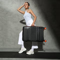 Black medium check-in suitcase with telescopic handle and corner wheels, front top visible