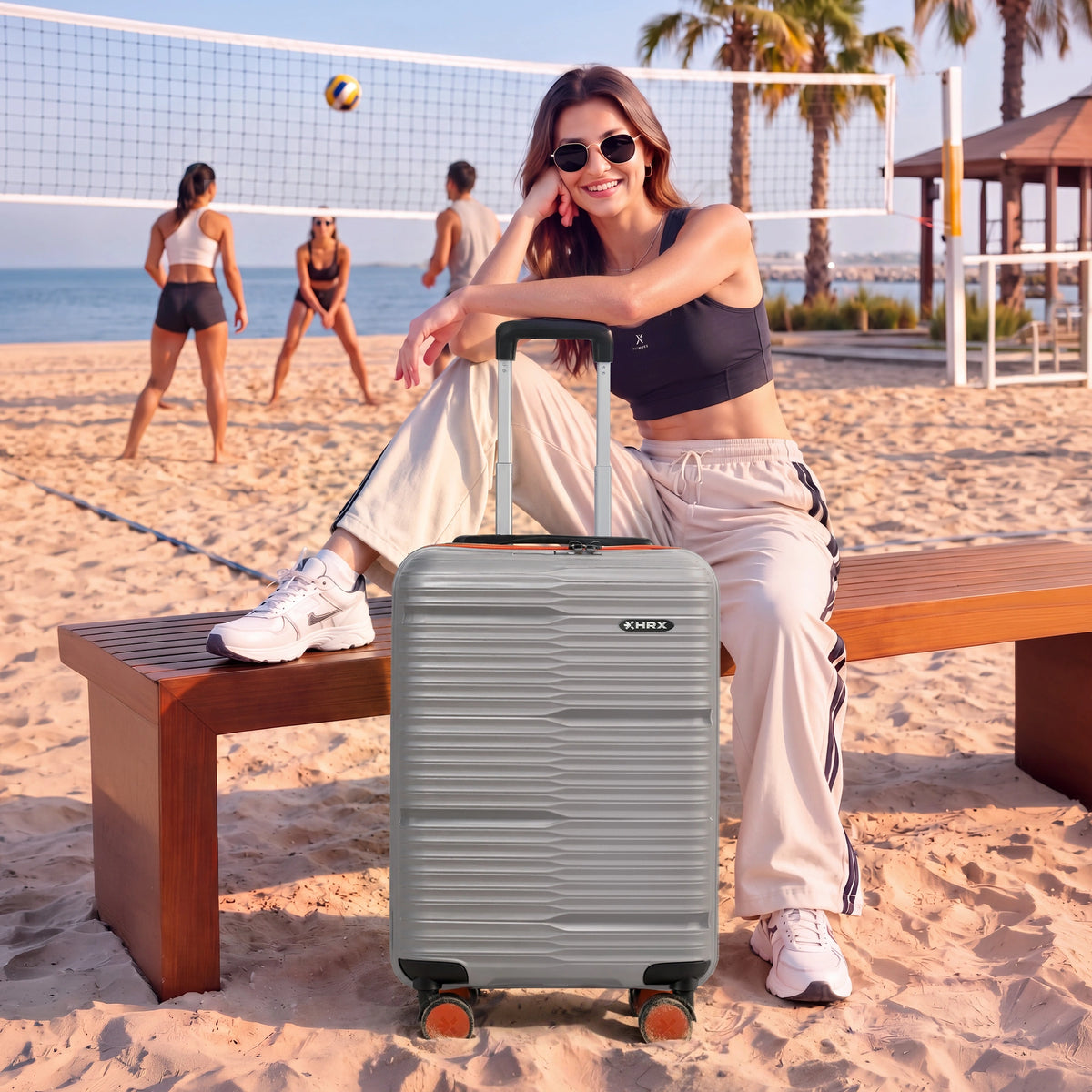 Medium check-in suitcase in light grey with textured finish and 8 spinner wheels, on sand