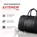 Black duffle bag with textured carbon-fiber finish and top handles on wet surface