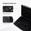 Hard-shell wheeled luggage open, showing dark interior compartments and straps.