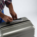 HRX check-in suitcase top with zipper track and size label, secured by hand